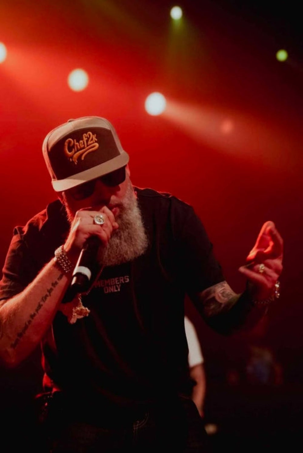 Performer wearing a CHEF2K embroidered cap onstage under red lighting